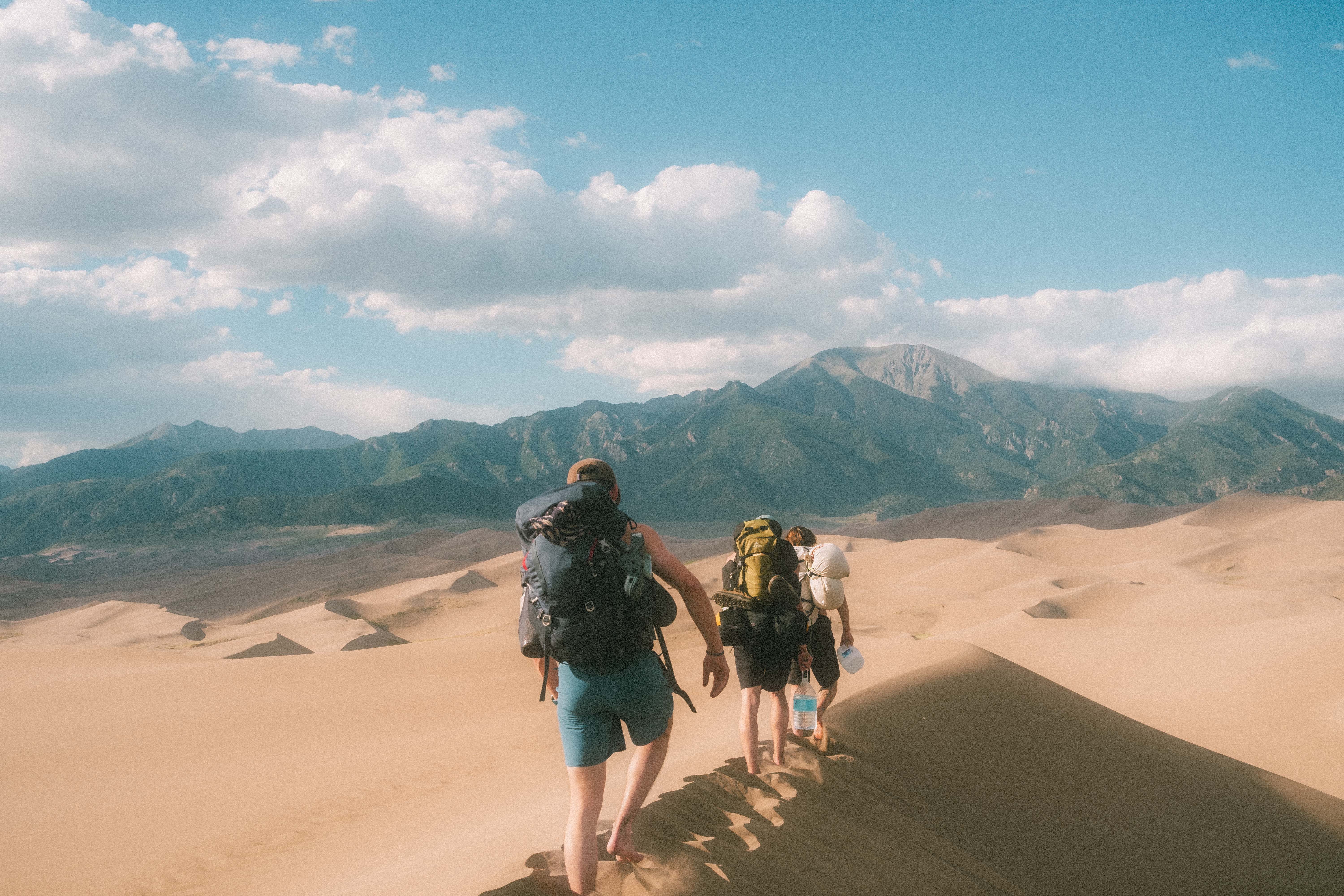 Hikers trekking across Great Sand Dunes with mountain backdrop
